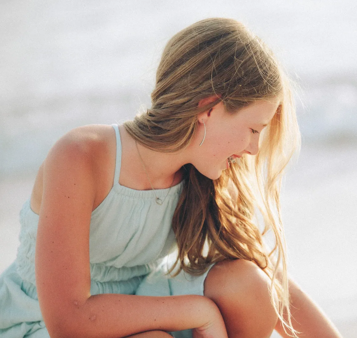 Girl in a pale blue dress looking down in soft light in Grand Cayman