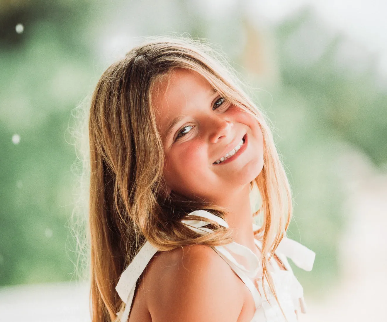 Smiling girl with long hair in a leafy garden in Grand Cayman