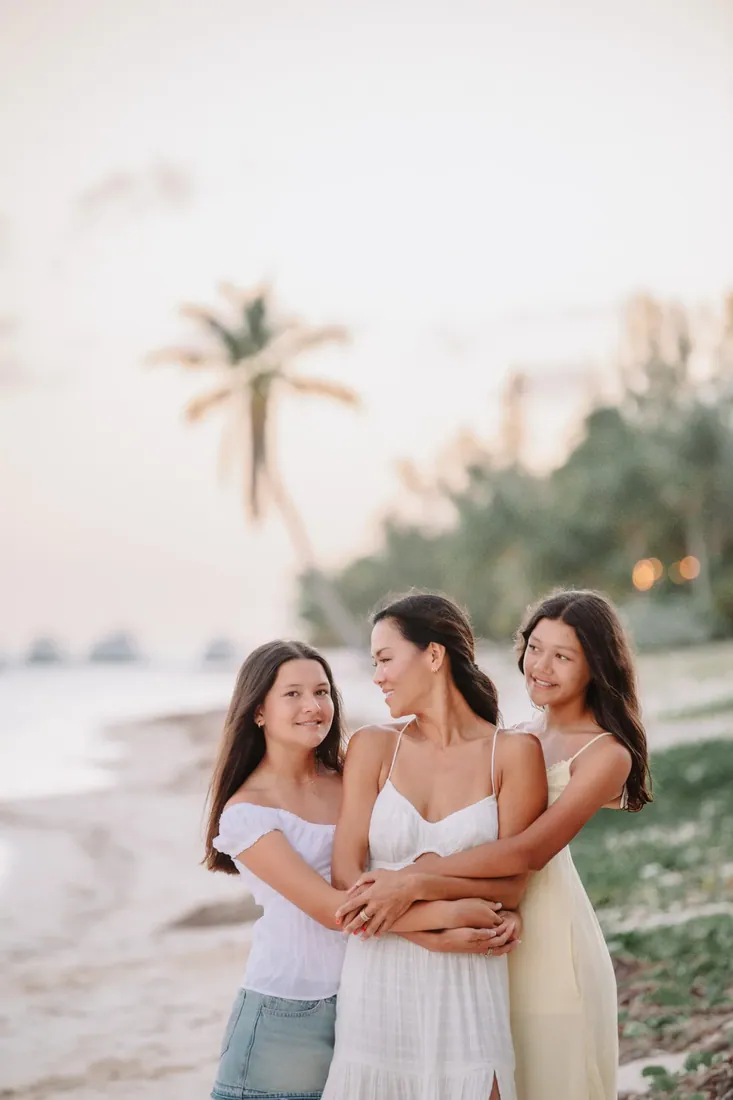 Mother and daughters embracing beneath palms in Grand Cayman
