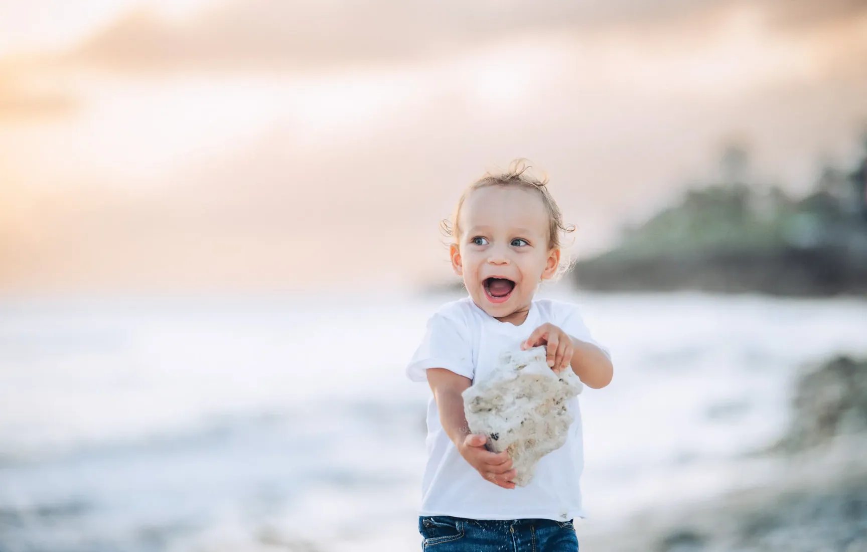 Little boy smiling beside the sea at sunset in Grand Cayman