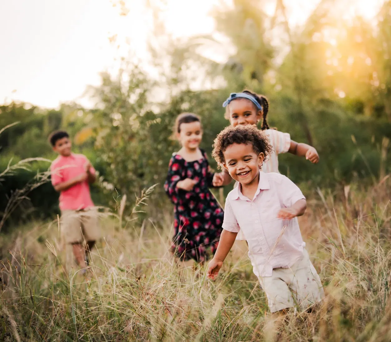 Children running together through golden grass in Grand Cayman