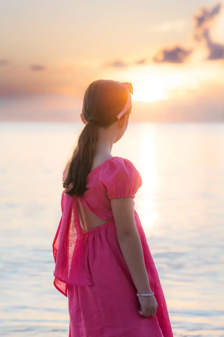 Girl in a pink dress looking towards the sunset in Grand Cayman
