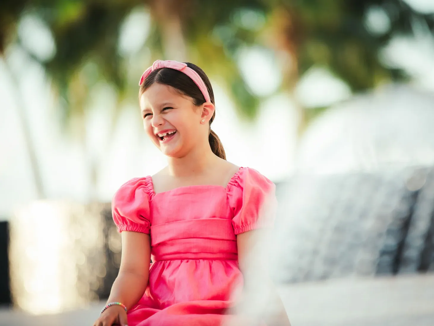 Girl in a pink dress smiling beneath palms in Grand Cayman