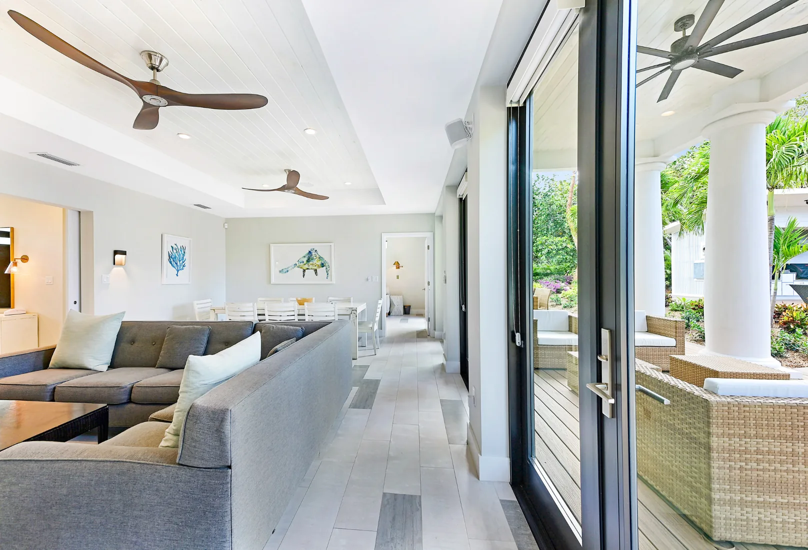 Living room with a grey sectional opening onto a covered wooden deck in Grand Cayman