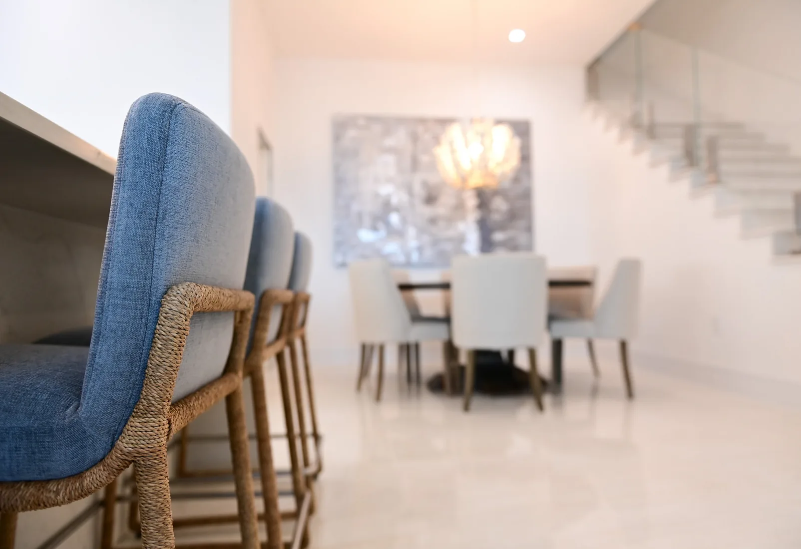 Rope-wrapped barstools at a kitchen island with a dining area beyond in Grand Cayman