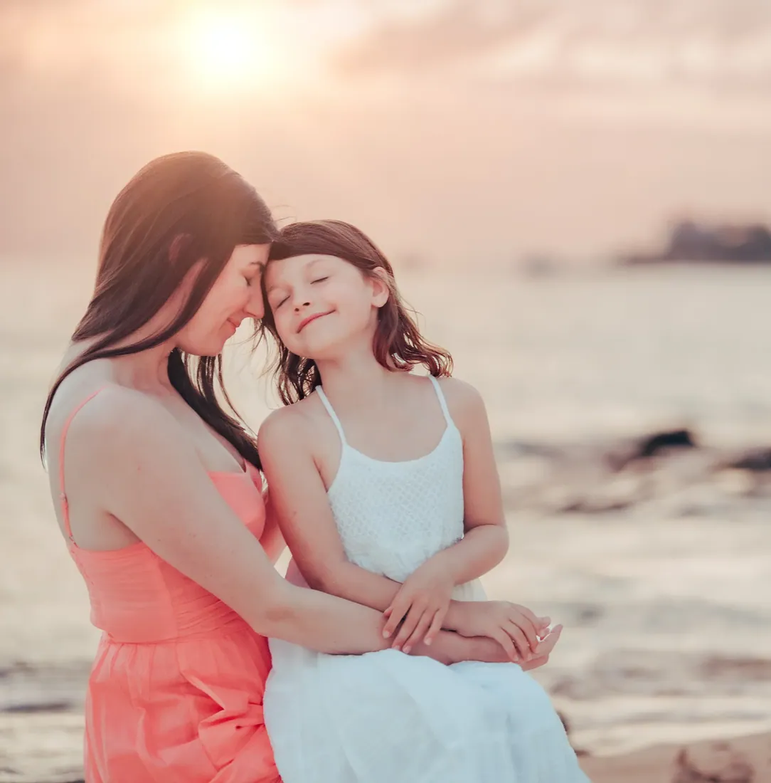 Mother cuddling her daughter beside the sea in Grand Cayman