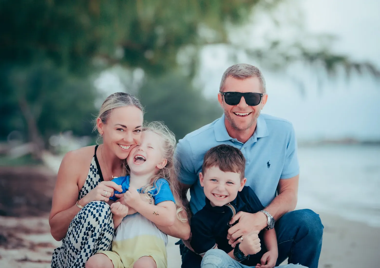 Parents seated with their young sons by the sea in Grand Cayman