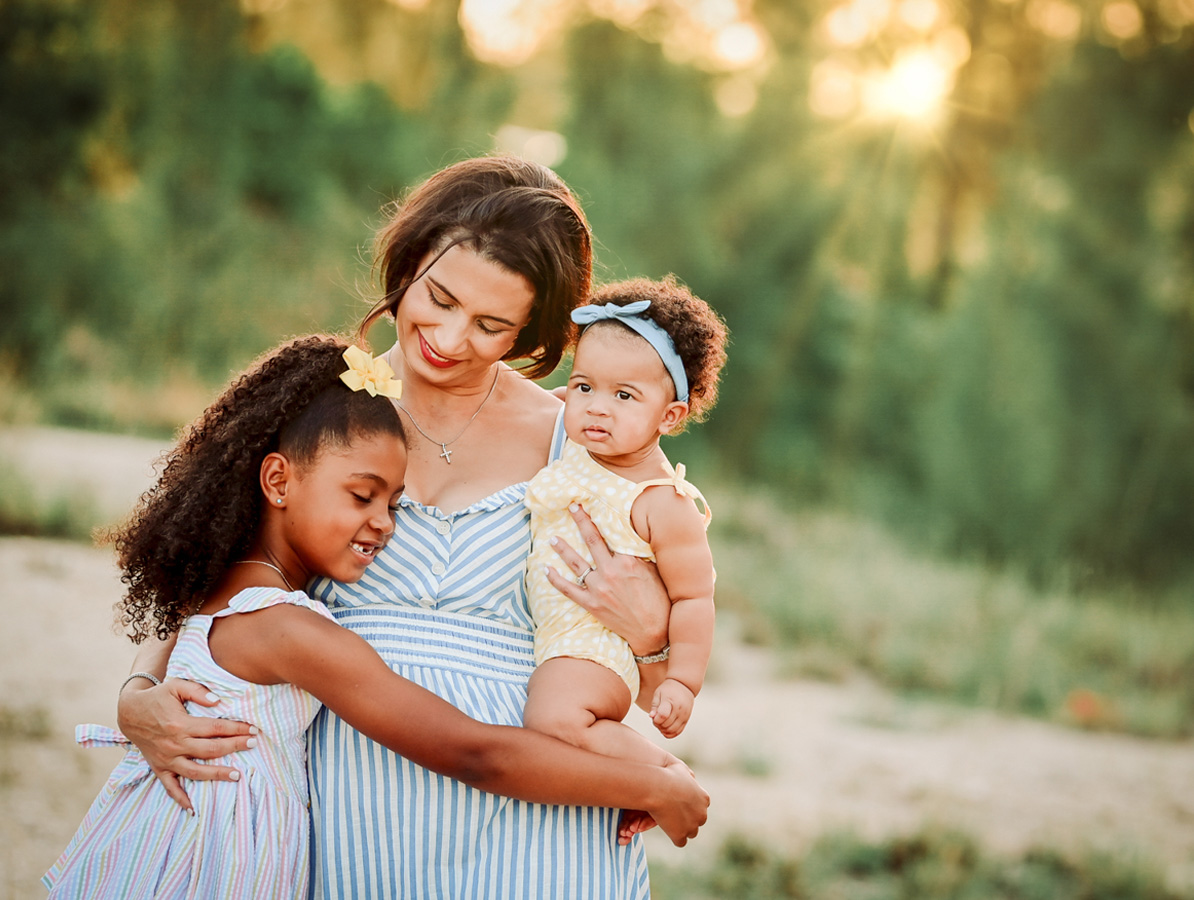 Mother holding her daughters in golden light