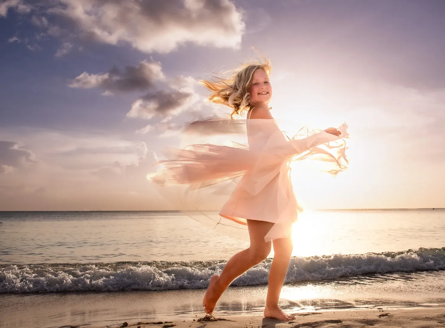 Girl twirling a pale dress on the beach at sunset in Grand Cayman