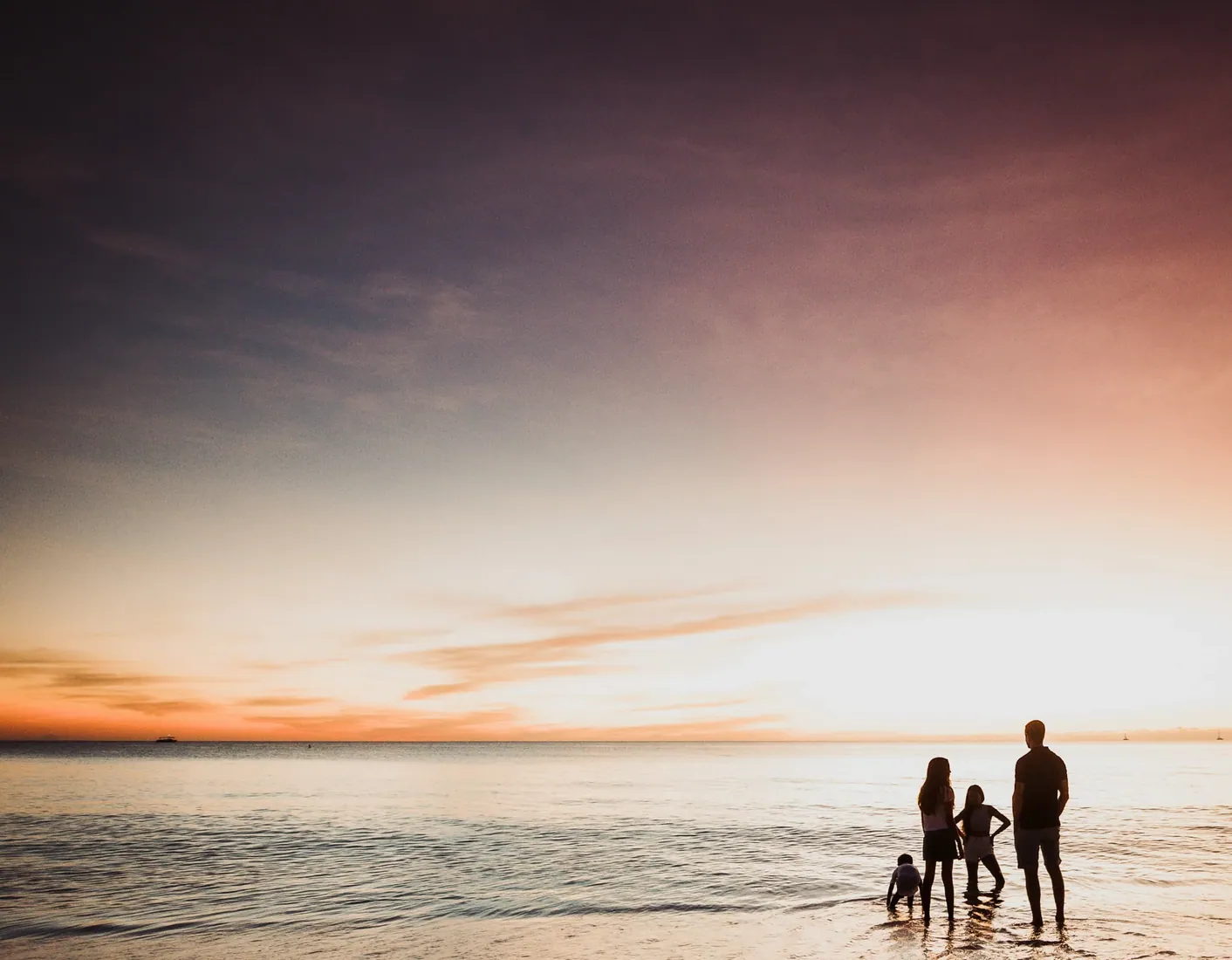 Family standing on the shoreline at sunset in Grand Cayman