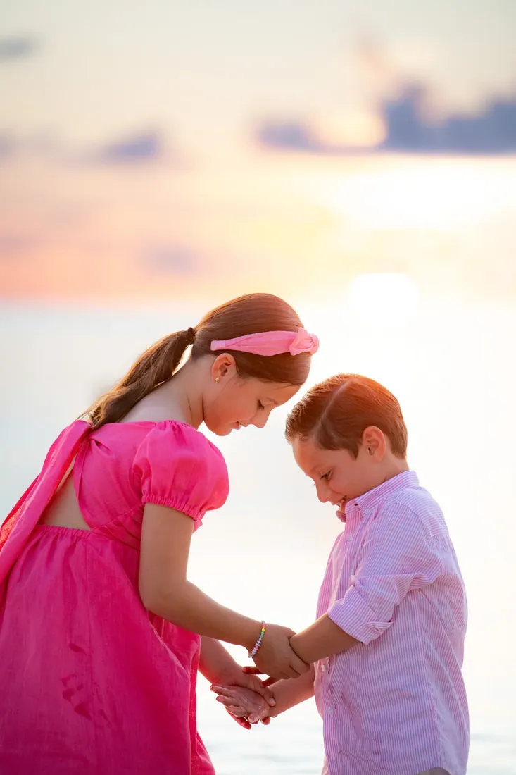 Girl greeting a young boy beside the sea at sunset in Grand Cayman