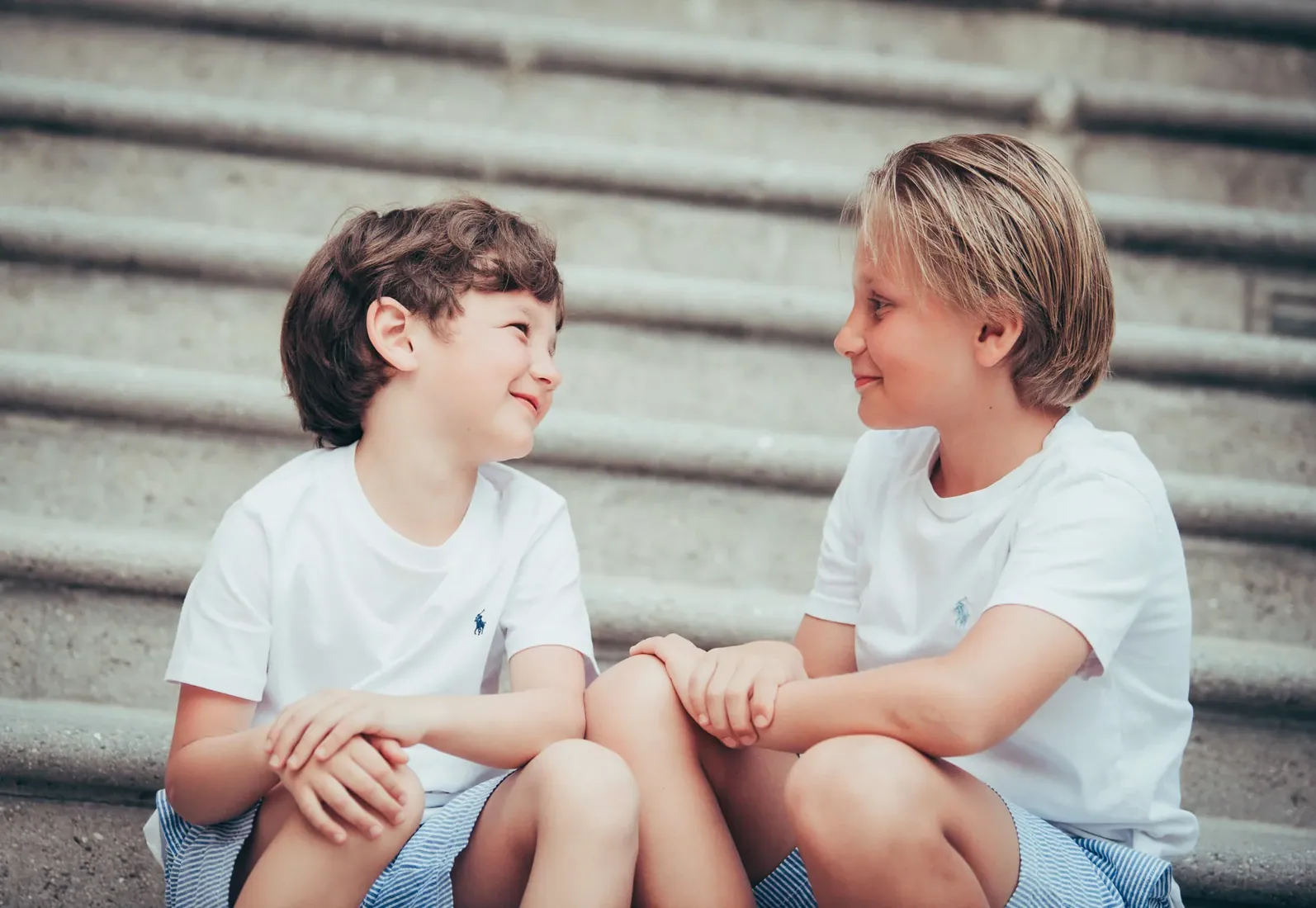 Two boys laughing together on outdoor steps in Grand Cayman
