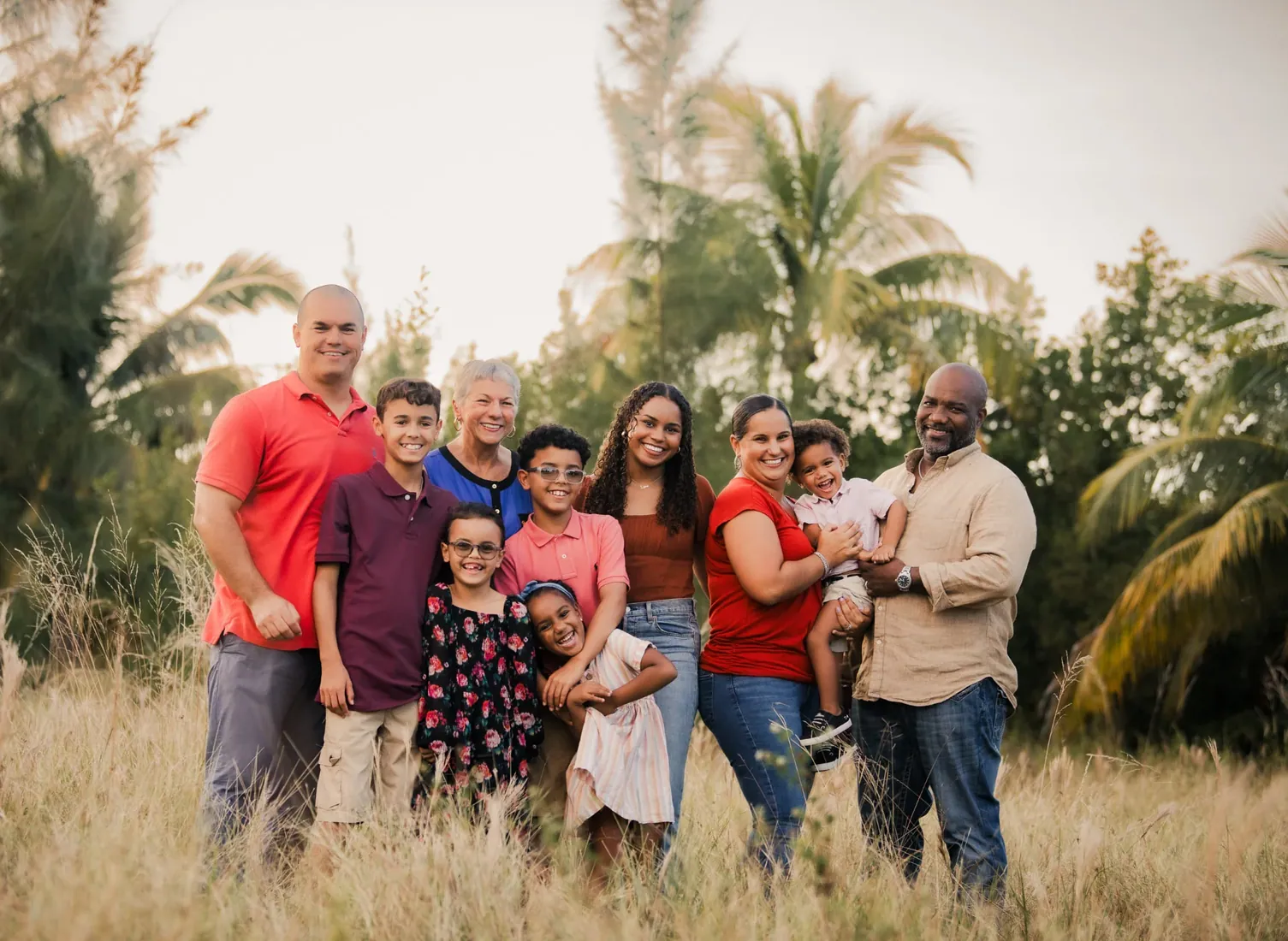 Extended family standing together beneath palms in Grand Cayman