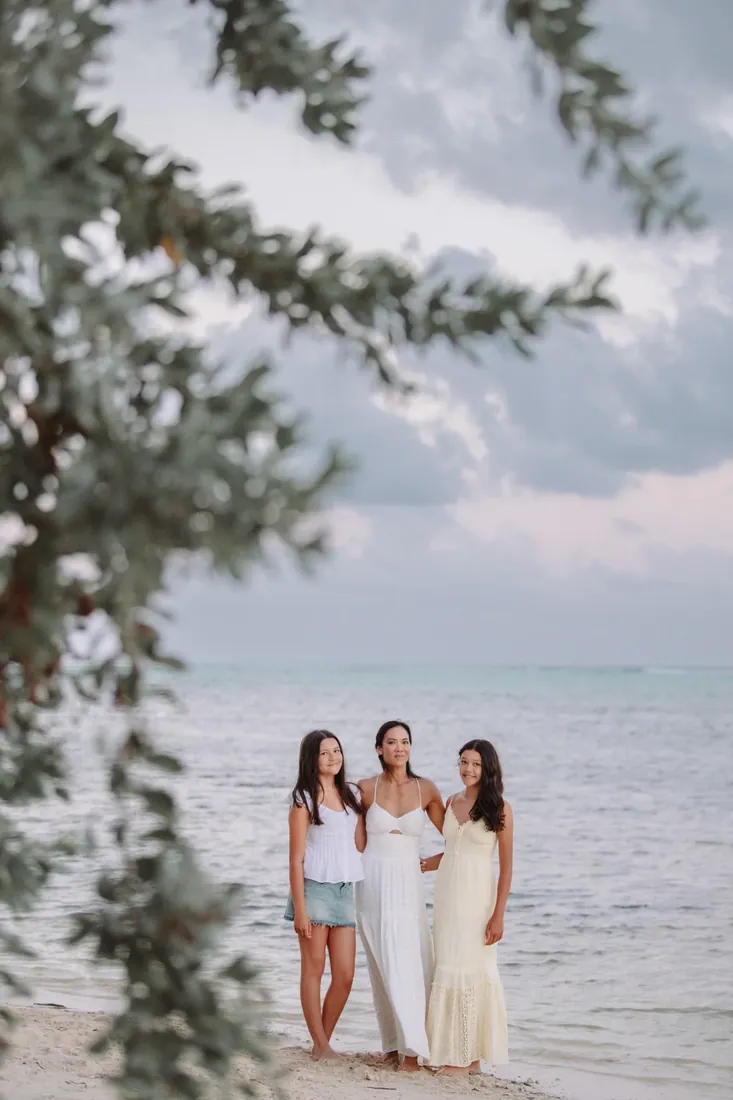 Family standing beside trees on a quiet beach in Grand Cayman