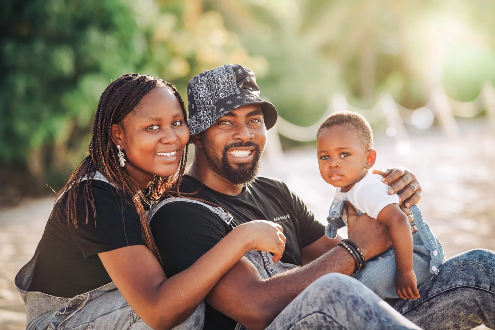 Parents smiling with their baby beneath trees in Grand Cayman