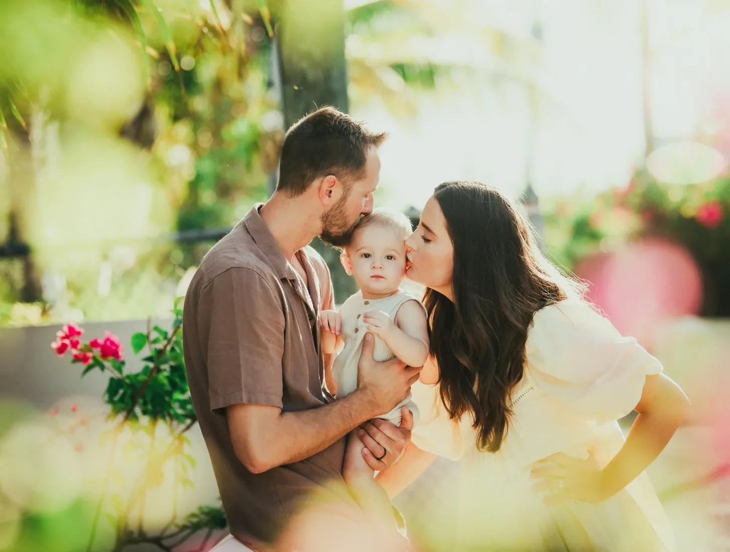 Parents kissing their baby in a tropical garden in Grand Cayman