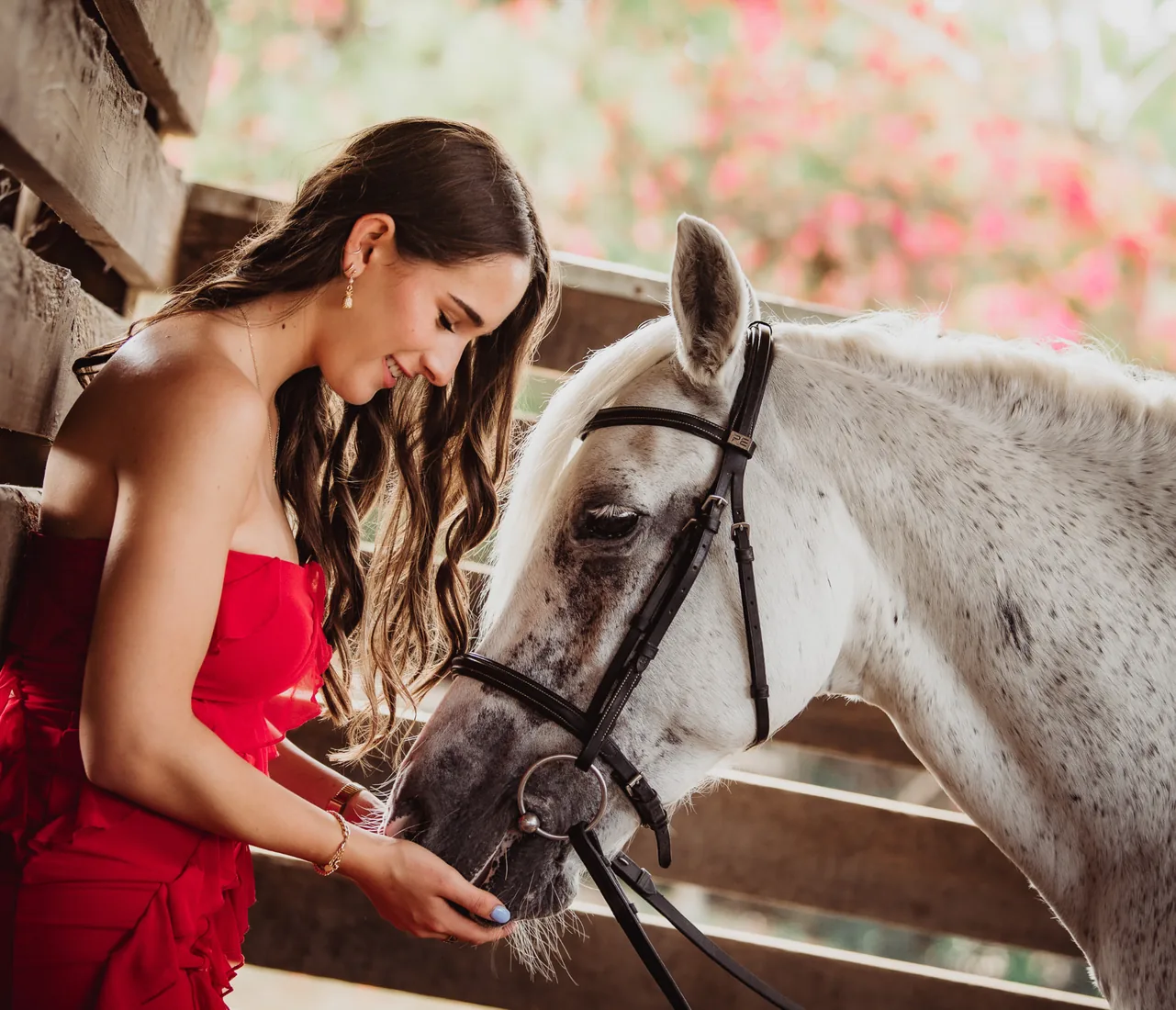 Woman in a red dress petting her white horse in Grand Cayman