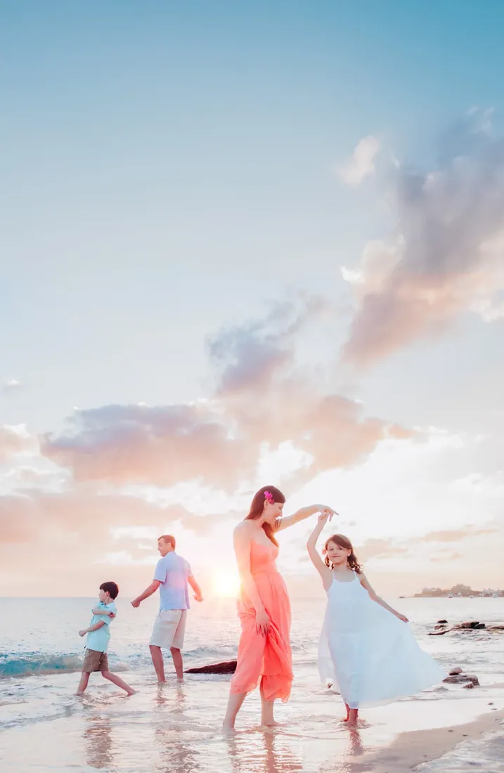 Mother twirling her daughter beside her family on a Grand Cayman beach at sunset