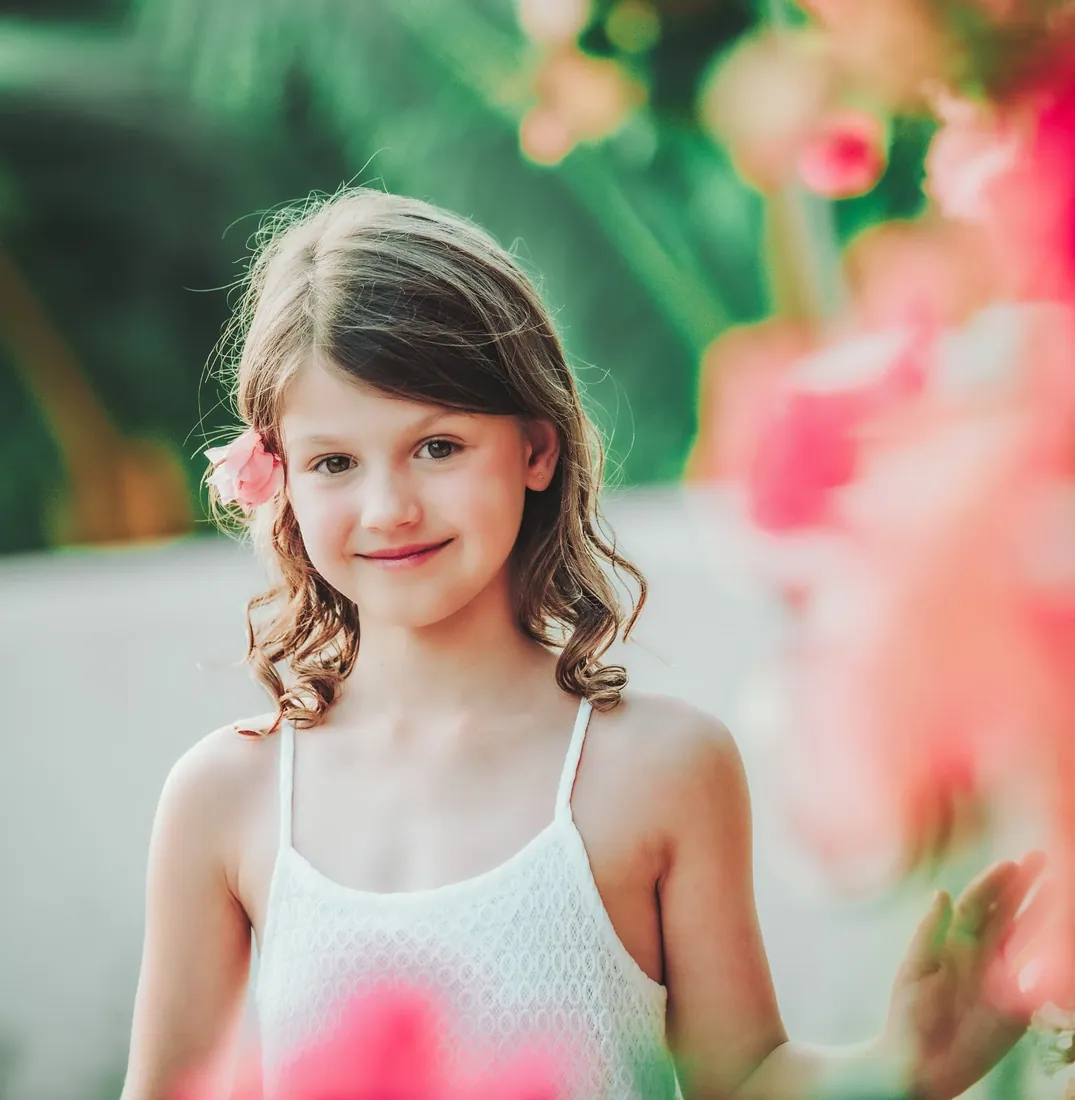Girl holding pink flowers in a tropical garden in Grand Cayman
