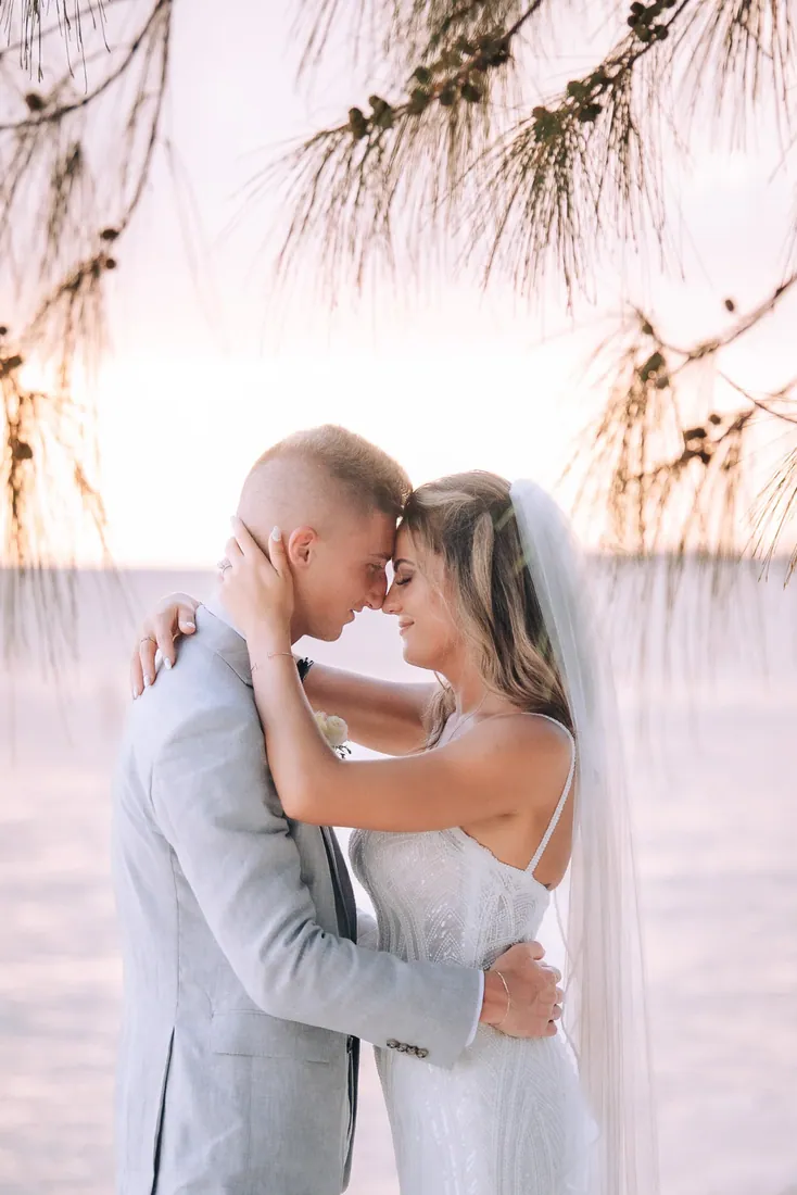 Bride and groom embracing beneath beach trees in Grand Cayman