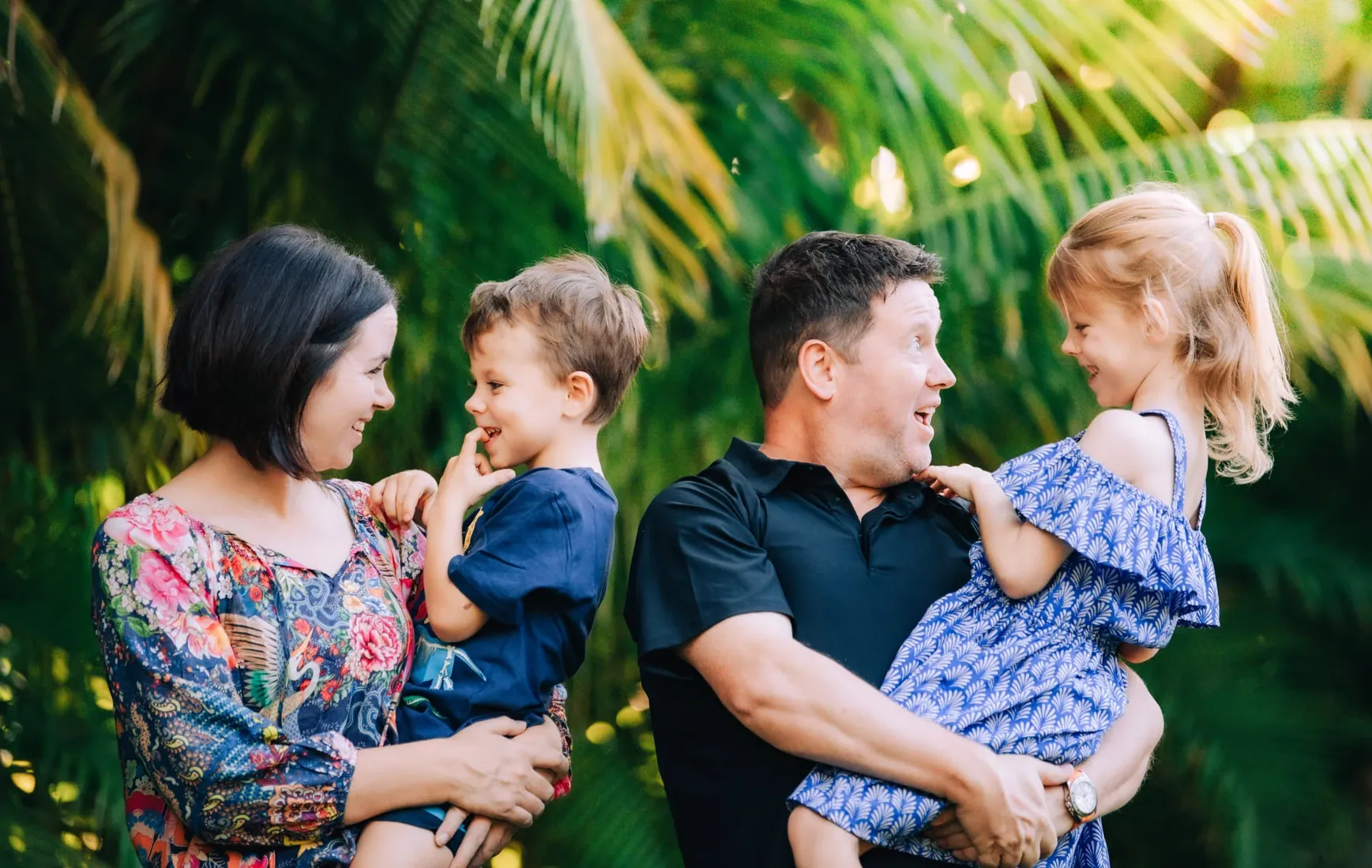 Parents laughing with their children beneath palms in Grand Cayman