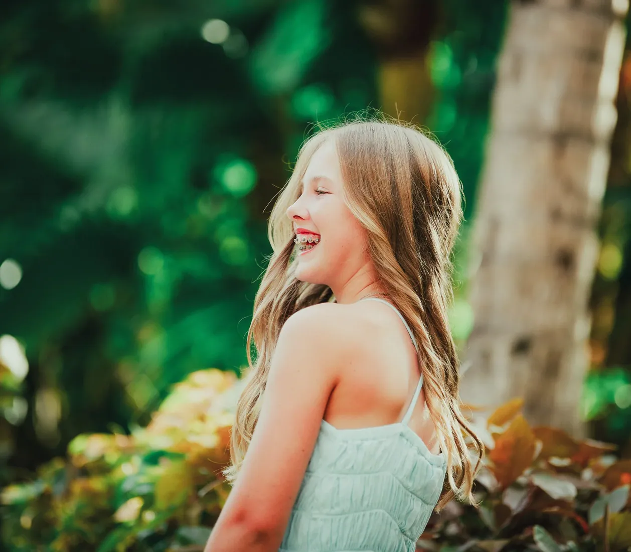 Girl in a pale dress laughing beside a tree in Grand Cayman