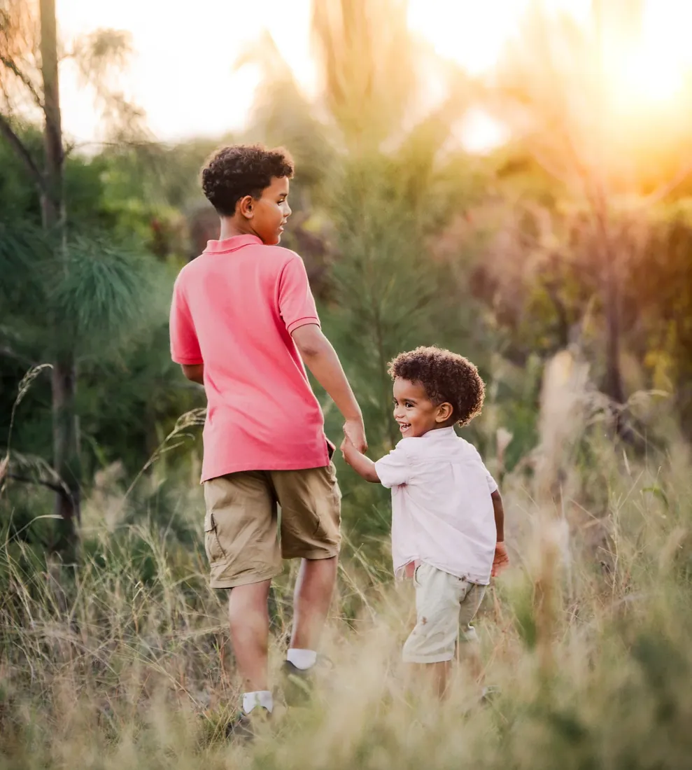 Boys walking together in a sunlit field in Grand Cayman