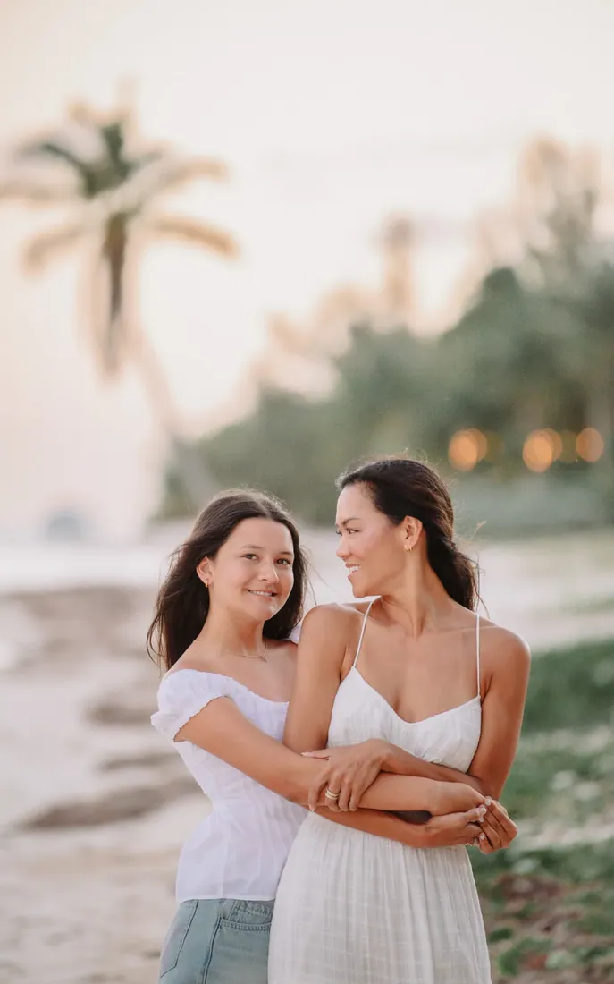 Mother embracing her grown daughters on the beach in Grand Cayman