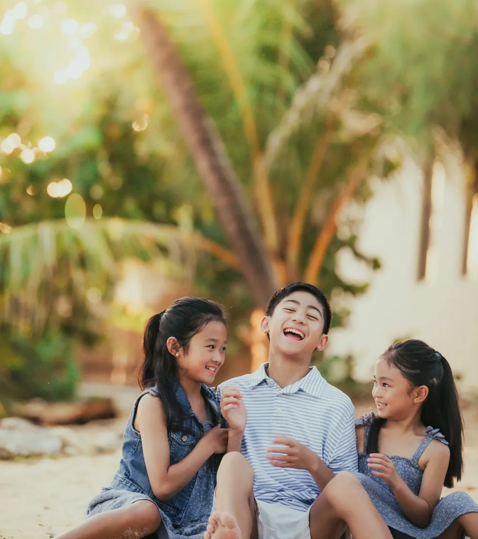 Family seated beneath trees in warm light in Grand Cayman