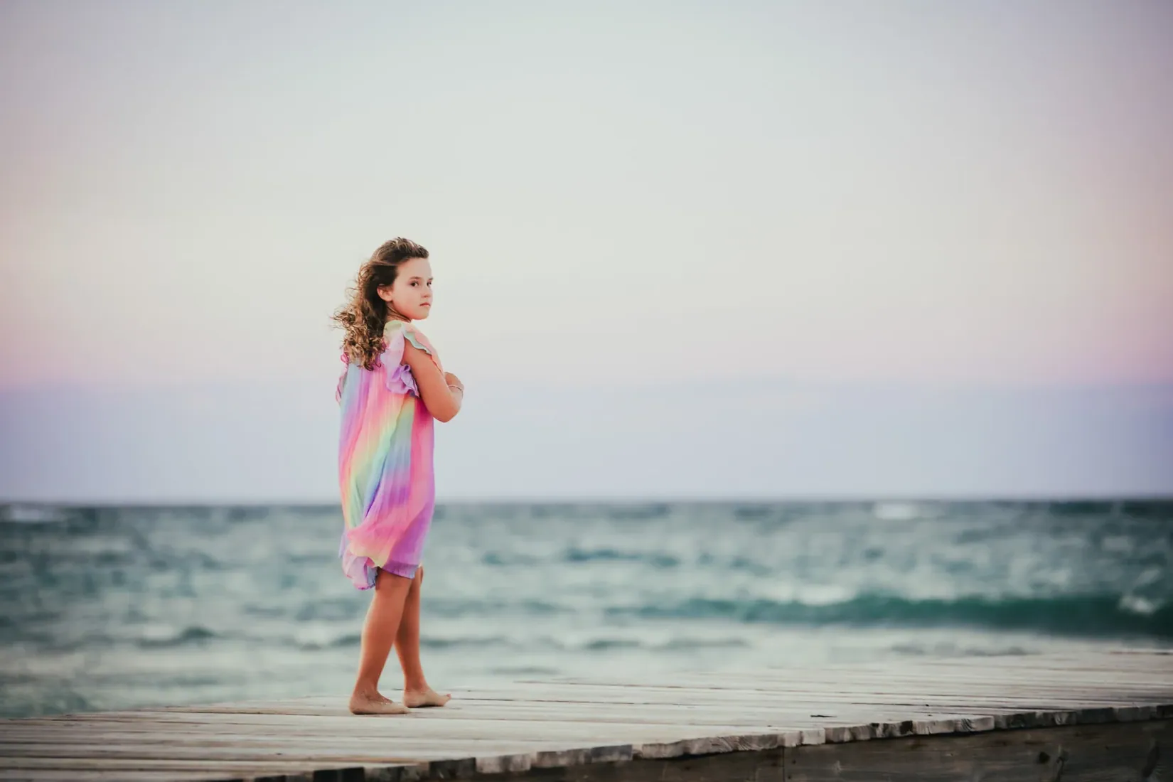 Girl walking along the shoreline with a colourful scarf in Grand Cayman